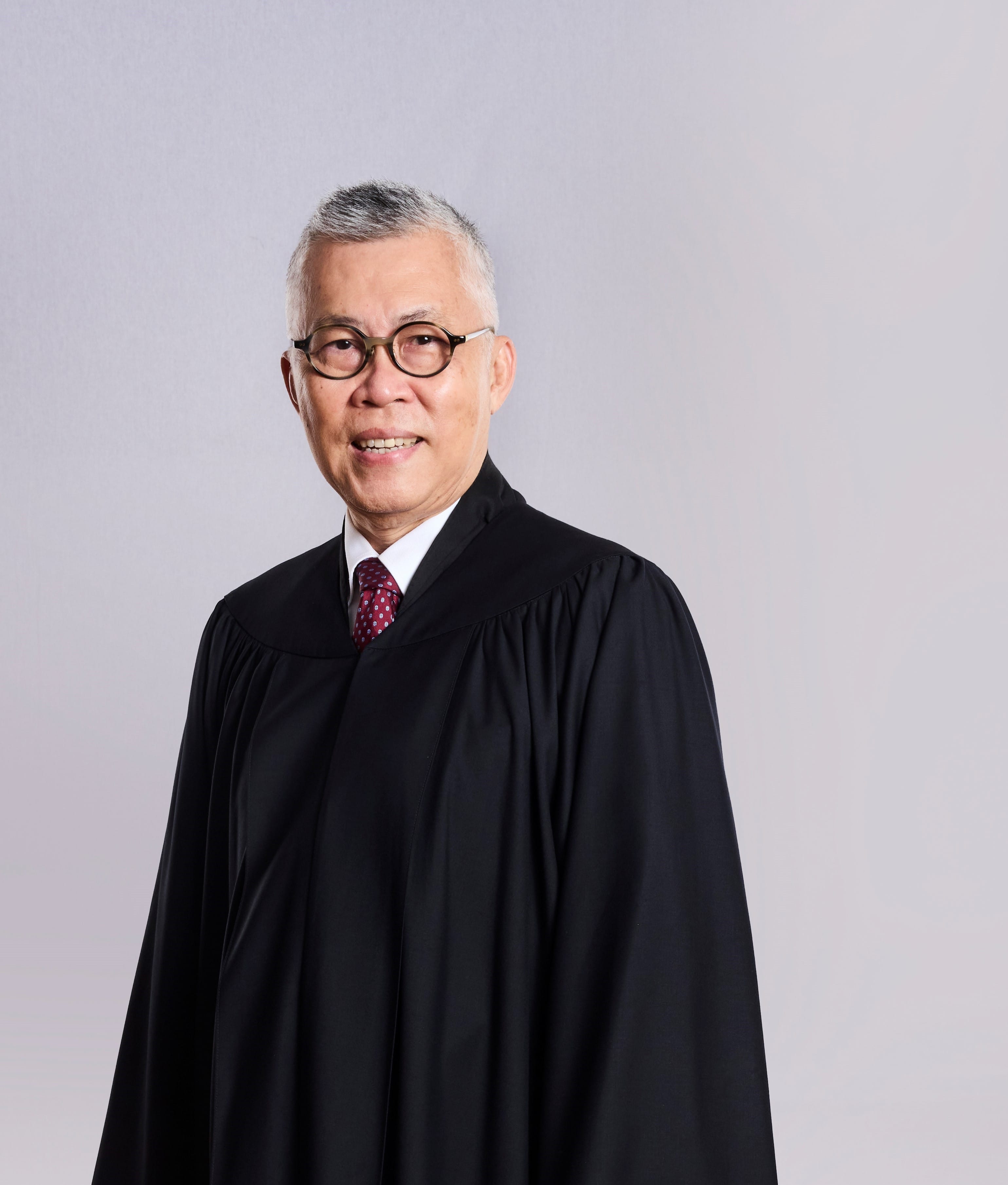 Person with gray hair, wearing glasses and black judge's robe.